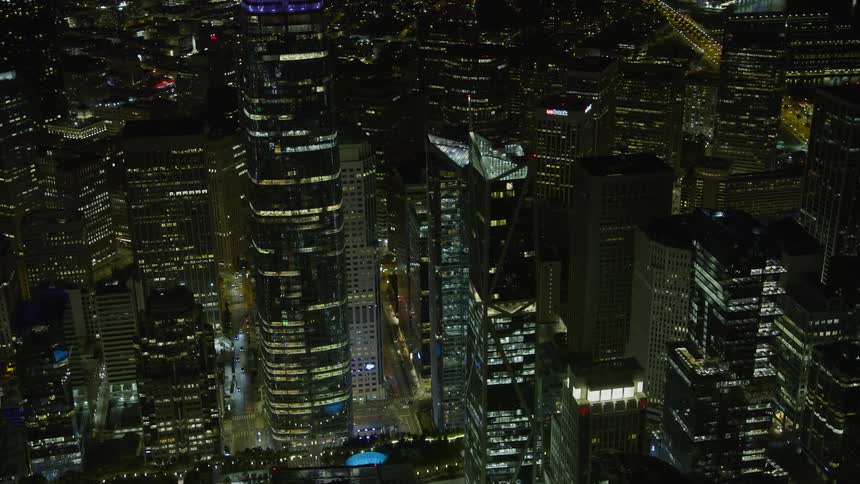 A stunningaerial footage showcasing the illuminated skyscrapers of Downtown San Francisco orbiting through the clear night skies of California capturing the modern cityscape and its iconic landmarks such as the Millennium Tower Salesforce Tower and 181 Fr