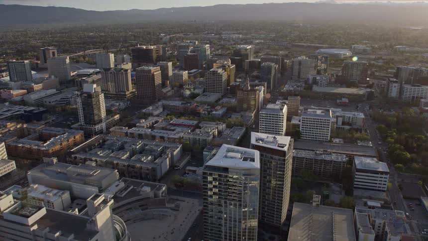 Breathtaking aerial view of office and apartment buildings in Downtown San Jose at sunset casting a hazy and mesmerizing glow over the city