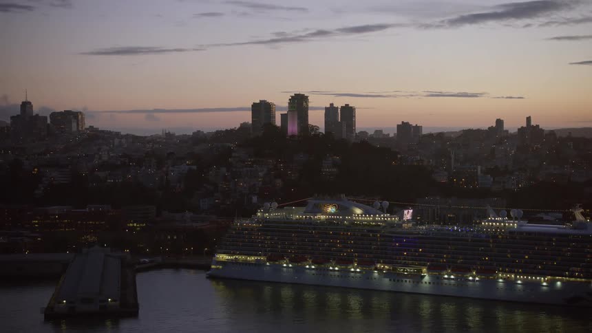 Aerial view of a cruise ship at twilight docked in the city with Coit Tower in the background providing a stunning shot of the San Francisco Bay Area