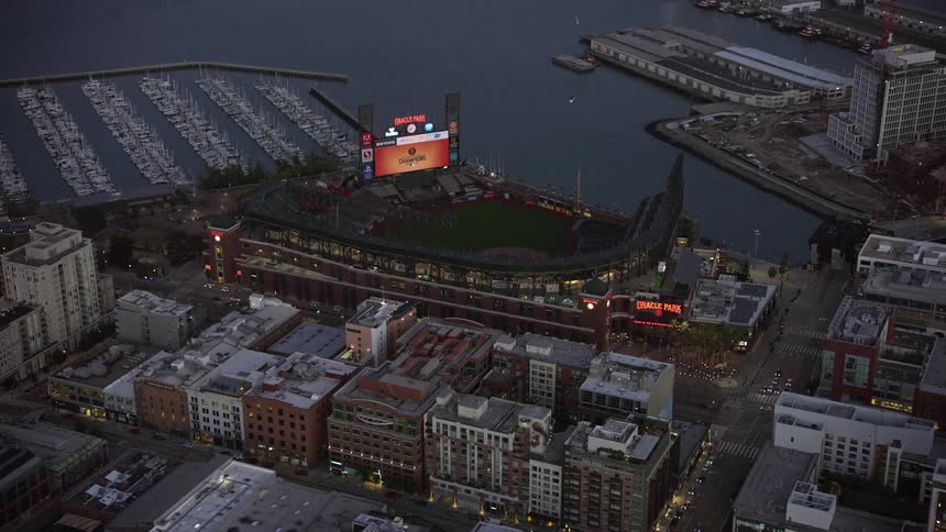  aerial footage of Oracle Park baseball stadium at twilight in California showcasing the stunning cityscape and waterfront location of this iconic sports venue
