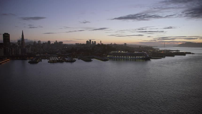 Aerial shot of a cruise ship docked near Coit Tower at twilight in San Francisco California