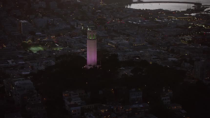  aerial footage capturing the iconic Coit Tower at twilight showcasing the historic landmark set against a partly cloudy sky in San Francisco California