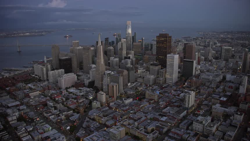  aerial footage capturing the breathtaking approach to Downtown San Francisco skyscrapers from Russian Hill during twilight showcasing the city's iconic transamerica pyramid and other supertalls against a backdrop of partly cloudy skies and the picturesqu