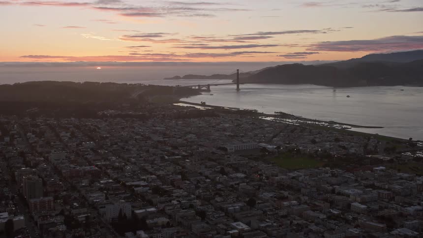 Aerial footage of a sunset over San Francisco with an approaching view of the city and the iconic Golden Gate Bridge