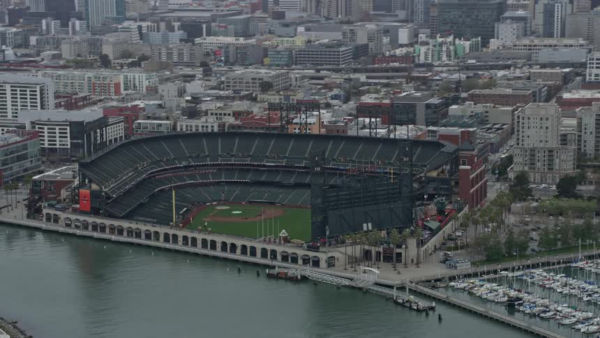  aerial footage of the Oracle Park baseball stadium in San Francisco California on a foggy day surrounded by water and boats during daytime