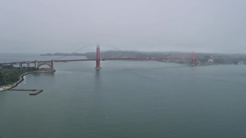  aerial footage captures the iconic Golden Gate Bridge shrouded in fog as it connects San Francisco to Marin County California on a misty overcast day