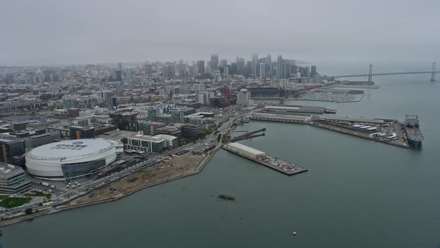  aerial footage of downtown San Francisco skyscrapers enveloped in fog captured from Chase Center in the Mission Bay area showcasing the city's iconic waterfront and supertall buildings on a misty day