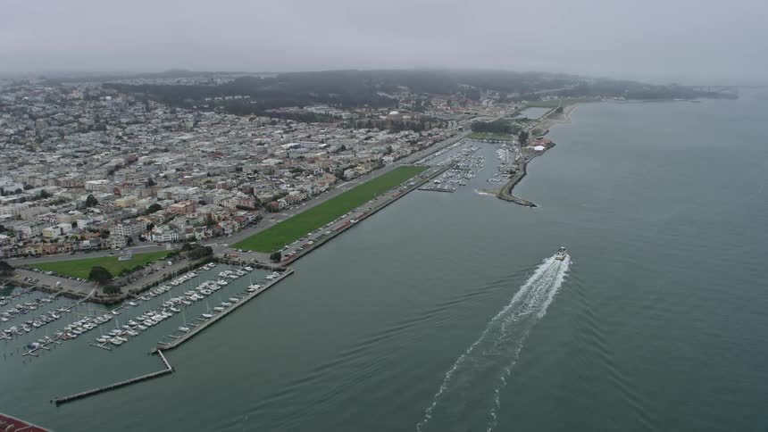  aerial footage of a flyover from Aquatic Park to Marina District in San Francisco California showcasing the city docks jetties and historic landmarks while approaching Fort Mason in the overcast day time scenery