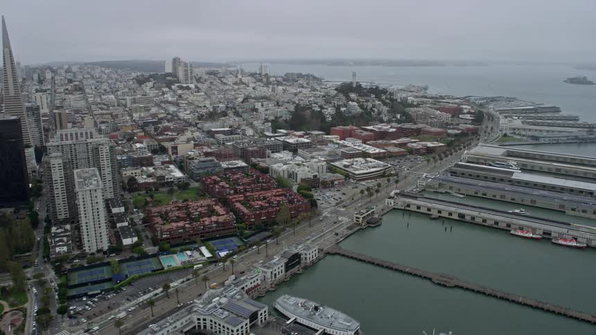  aerial footage captures a foggy flyby of Downtown San Francisco and Coit Tower iconic structures in the downtown area on a cloudy day in Northern California
