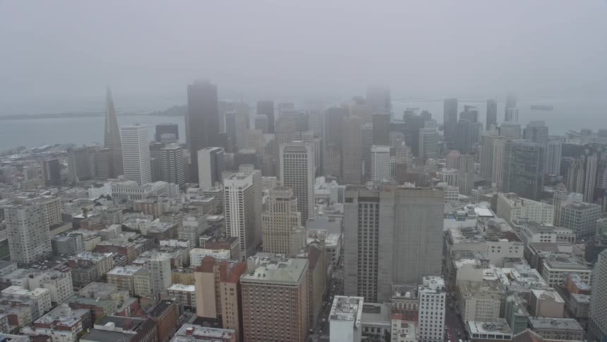  aerial footage capturing the fog-covered downtown skyscrapers of San Francisco on a overcast day in California providing a side view of the city's high rises and epic superstructures