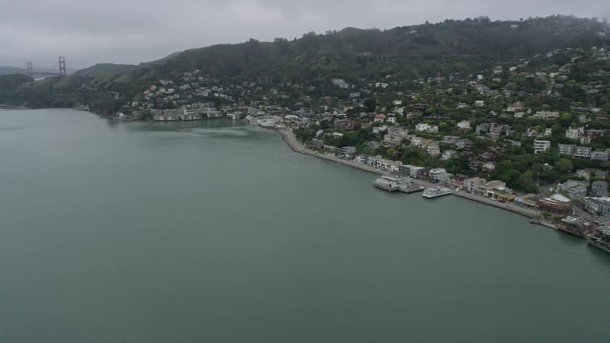  aerial footage capturing the foggy coastal neighborhoods of Sausalito California showcasing the stunning shoreline and residential areas on a foggy day