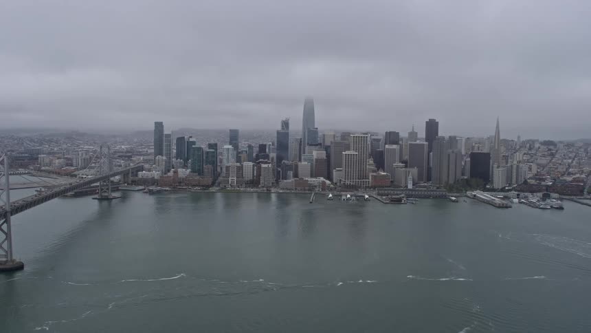  aerial footage of Downtown San Francisco shrouded in fog viewed from the bay on a cloudy day