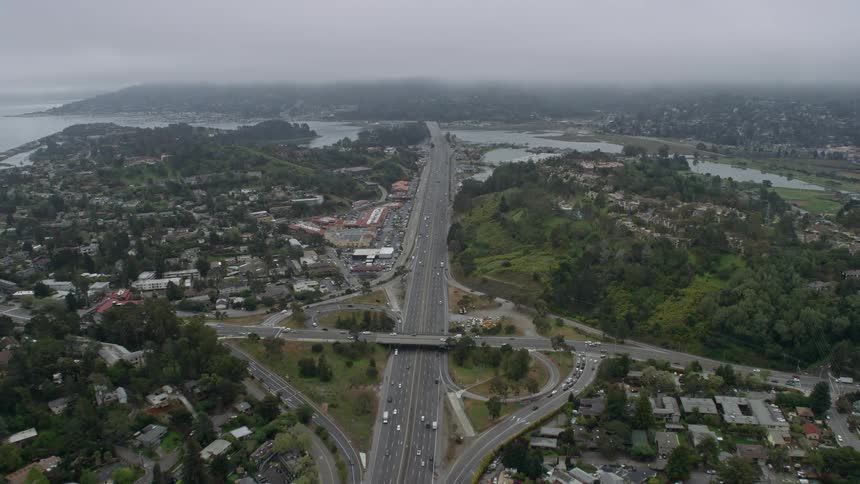 Aerial footage captures foggy day as Highway 101 winds through Mill Valley showcasing suburban neighborhoods and residential areas in Northern California