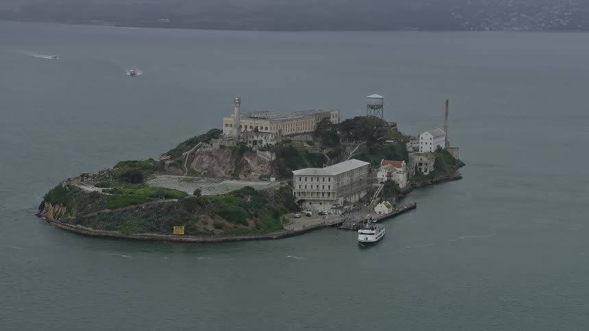  aerial footage of Alcatraz Island a historic landmark and government building in San Francisco Bay California captured on a foggy day showcasing its iconic structure and the surrounding bay area
