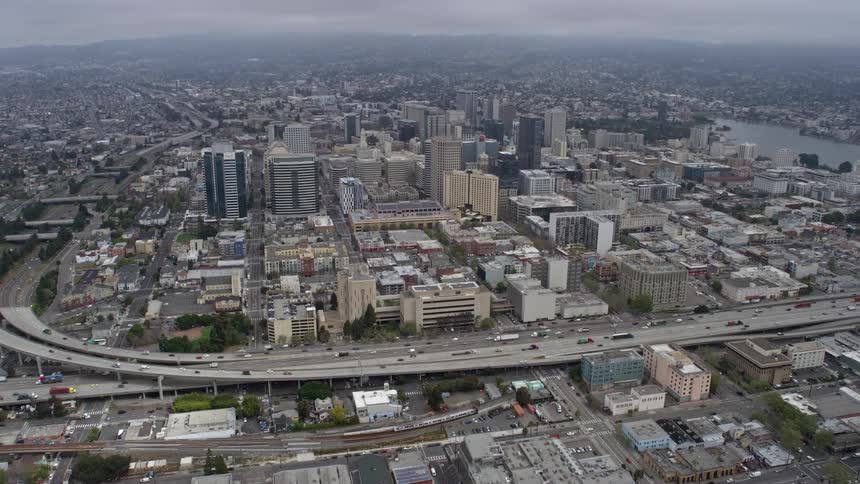  aerial footage captures the foggy and overcast day as the camera tilts up to reveal the industrial and office buildings of downtown Oakland California