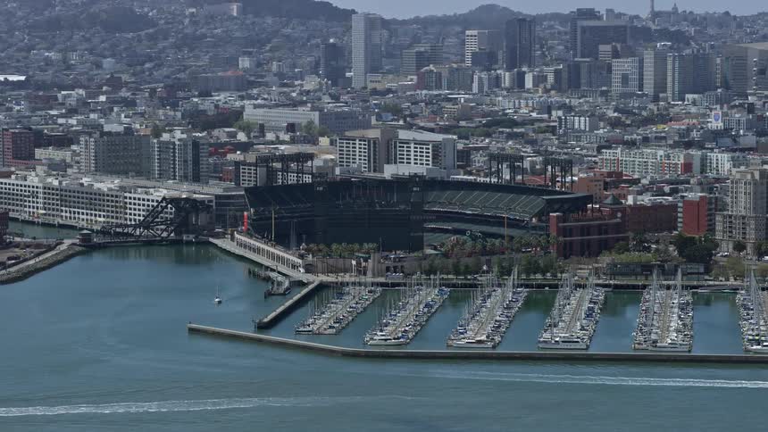  aerial footage showcasing a stunning reverse view of the waterfront baseball stadium located in the vibrant city of San Francisco California during a sunny day capturing the essence of outdoor recreation and sports in the Bay Area