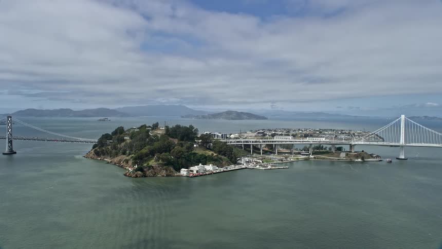 Aerial footage of cars driving over the bridges on the islands of Yerba Buena Island in San Francisco Bay California on a partly cloudy day