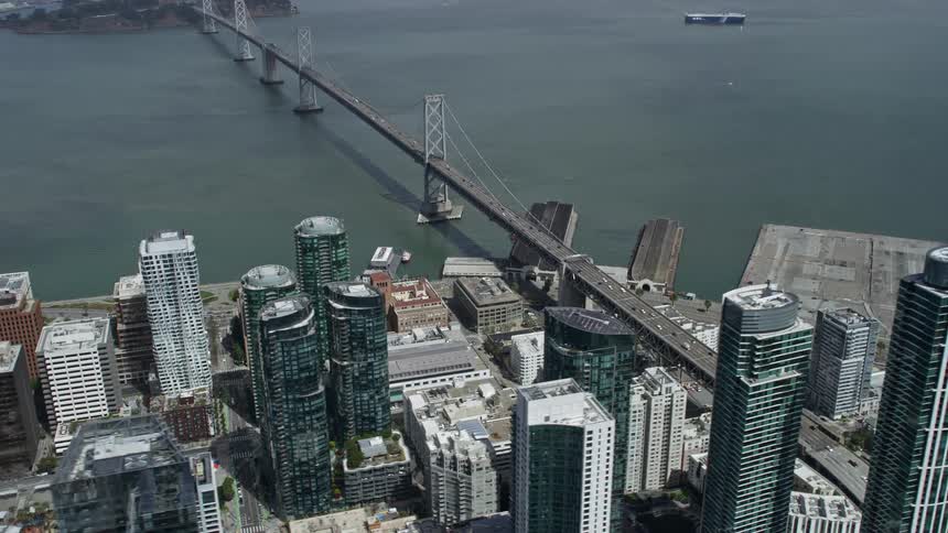 Aerial view of Downtown San Francisco and the Bay Bridge with skyscrapers and cars crossing showcasing the city's high-rise buildings and iconic suspension bridge
