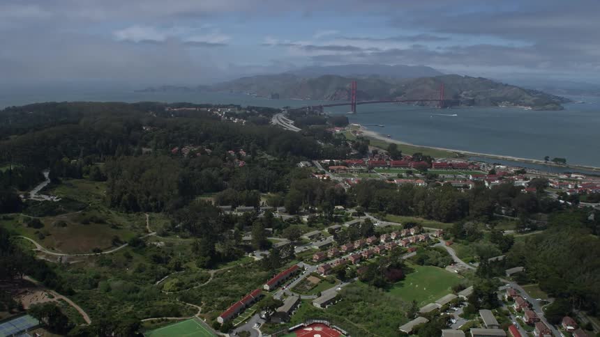  aerial footage of a tilt from Inner Richmond to reveal The Presidio and the iconic Golden Gate Bridge in San Francisco California as partly cloudy skies createscenery during the day
