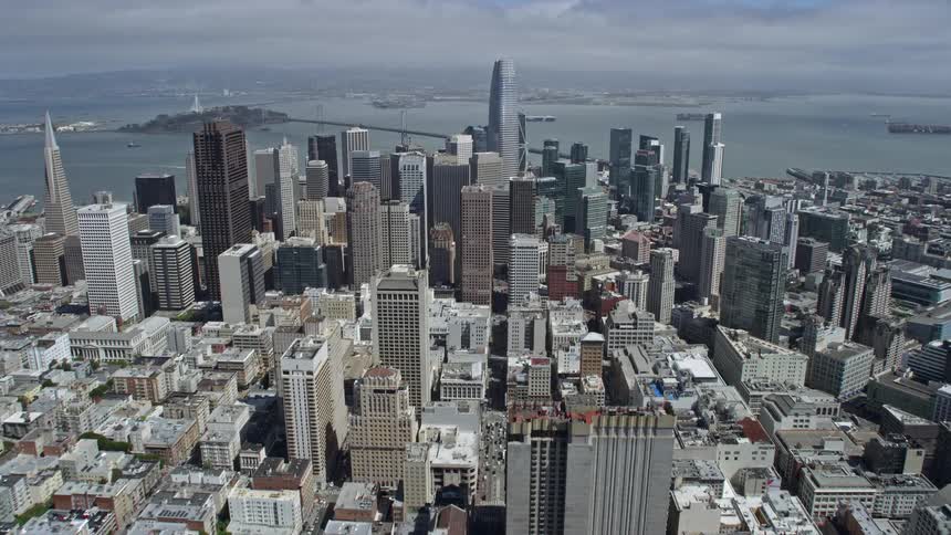 Aerial footage of Salesforce Tower and Downtown San Francisco California on a partly cloudy day capturing the high-rise buildings approaching in the wide-angle POV