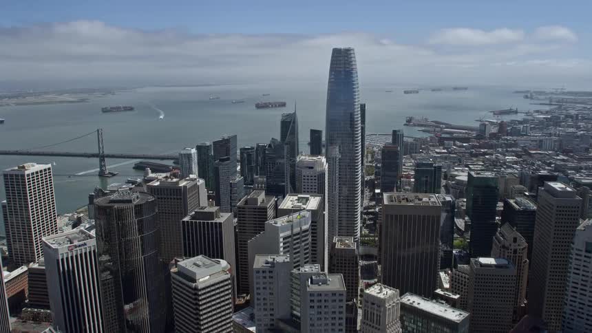  aerial footage capturing the approach and flyby of Salesforce Tower a high rise in downtown San Francisco California showcasing the city's skyline with partly cloudy skies during the day