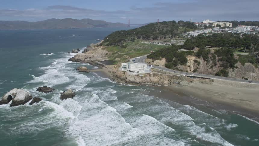 Aerial footage of the Cliff House on the coast overlooking Seal Rocks and the ocean with partly cloudy skies in San Francisco California during the day