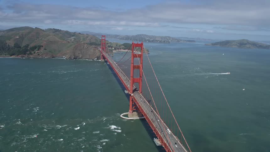 Stunningaerial footage captures vehicles crossing the iconic Golden Gate Bridge as part of the 101 freeway on a partly cloudy day in San Francisco California