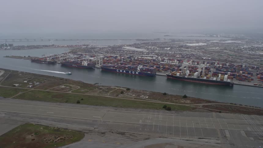 Aerial view of cargo ships docked at the bustling Port of Oakland California during a foggy day showcasing the industrial maritime scene of this busy shipping hub on the West Coast