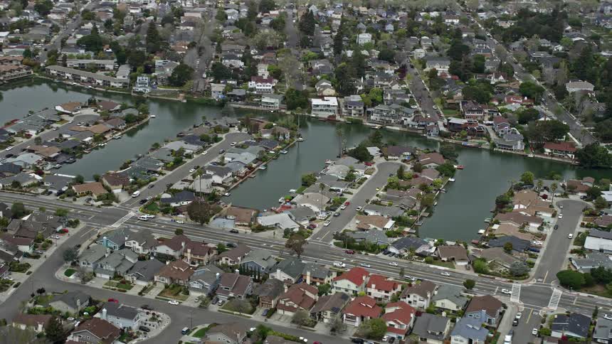  aerial footage showcasing beautiful waterfront homes alongside canals in the suburban neighborhood of Alameda California on a cloudy day