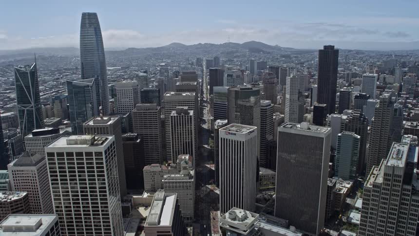  aerial footage of a partly cloudy day as we ascend over the Ferry Building and Downtown San Francisco capturing the cityscape and iconic structures of this historic landmark in the Bay Area of California
