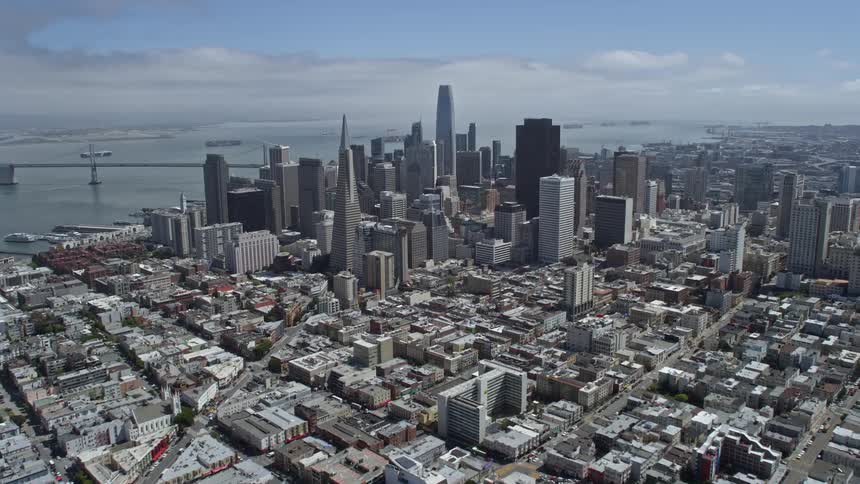 A mesmerizingaerial view of the Downtown San Francisco skyline as it is approached from Russian Hill on a partly cloudy day showcasing the high-rise towers and iconic cityscape of this vibrant city on the west coast with a wide-angle POV flyover capturing