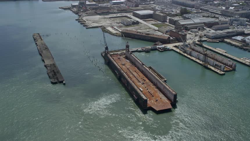 Aerial footage of a dry dock in San Francisco California on a sunny day approaching the waterfront with sunshine and clear skies