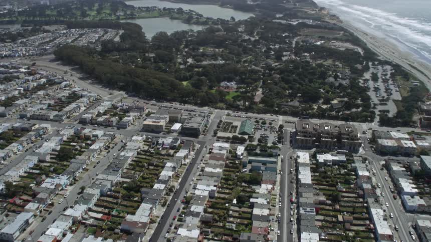 aerial footage captures a scenic flyover of Outer Sunset District homes with a tilt to the nearby shops in San Francisco California on a partly cloudy day