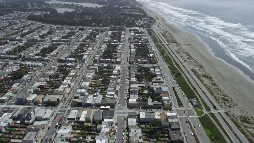 Aerial view of homes near Ocean Beach in the Outer Sunset District of San Francisco with traffic moving along neighborhood streets paralleling the beach
