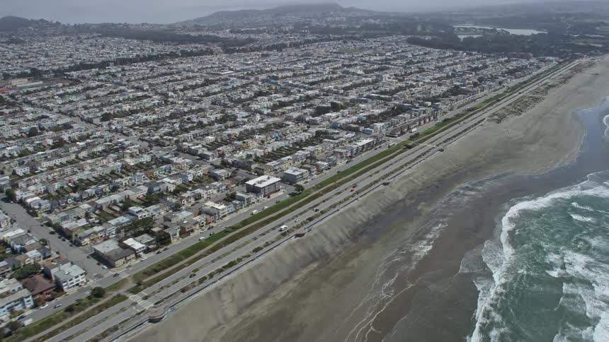  aerial footage of a residential area in the Outer Sunset District San Francisco California near Ocean Beach showcasing a highway and coastline on a partly cloudy day