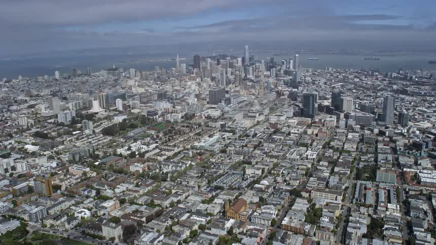 Aerial view of downtown San Francisco California passing Alamo Square Park on a cloudy day with skyscrapers and cityscape in the background