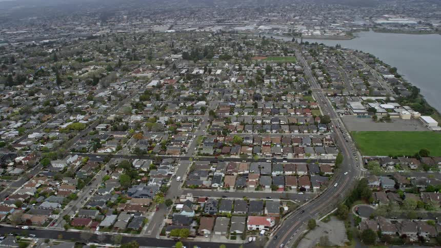 aerial shot flying past suburban neighborhoods in Alameda California capturing the sunny and cloudy skies of this residential area on the West Coast during the summer