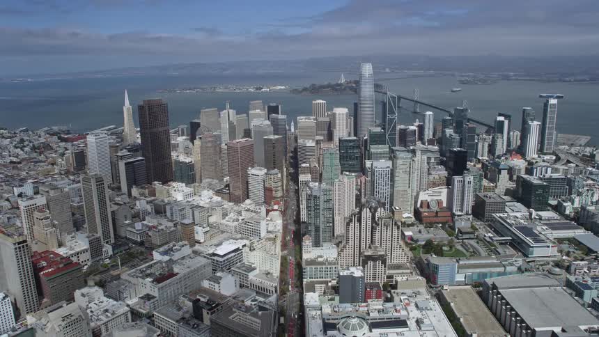  aerial footage flying over Market Street and downtown San Francisco capturing high rise buildings city streets and the skyline on a cloudy day in the Bay Area with a wide angle view and approaching perspective