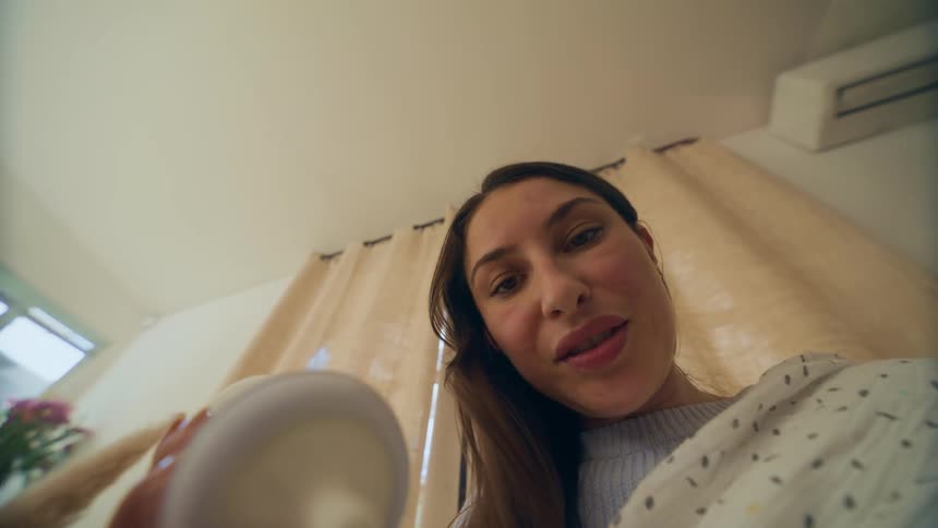 Point of view of a womans face holding a bottle with a blanket over her shoulder