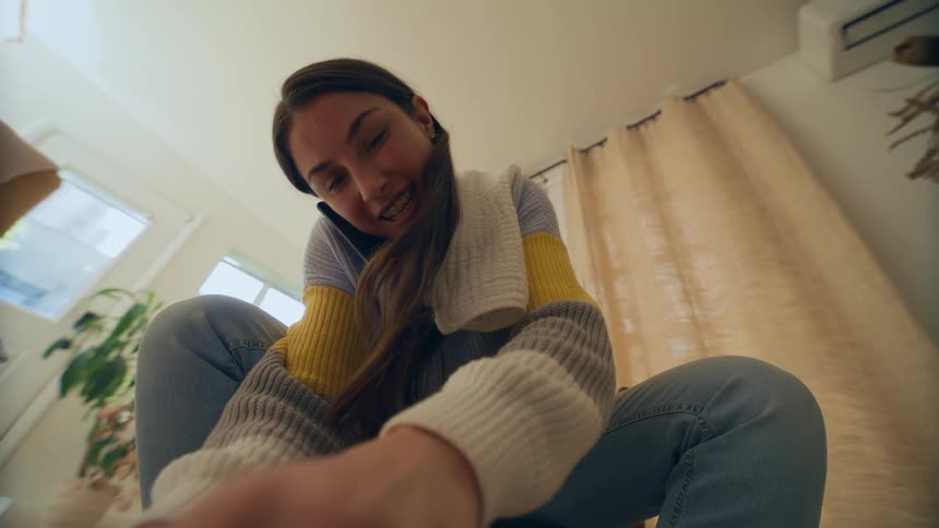 Woman sitting talking on the phone while opening a diaper and holding a toy