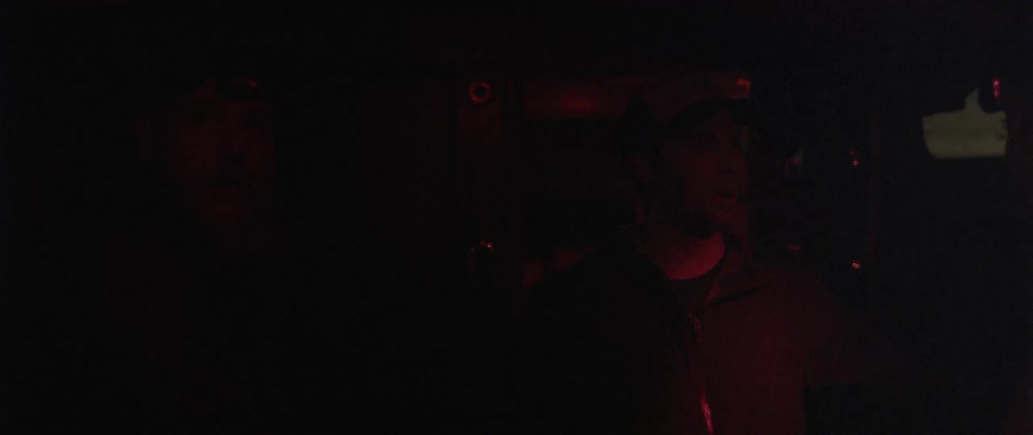 A man who is talking is bathed in a red light