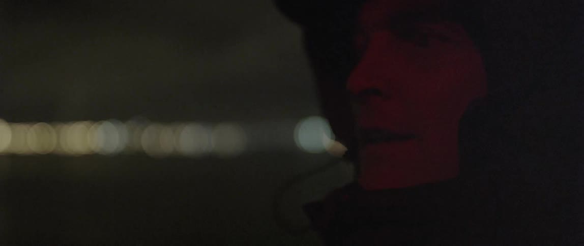 Man with hood over his head staring off at night