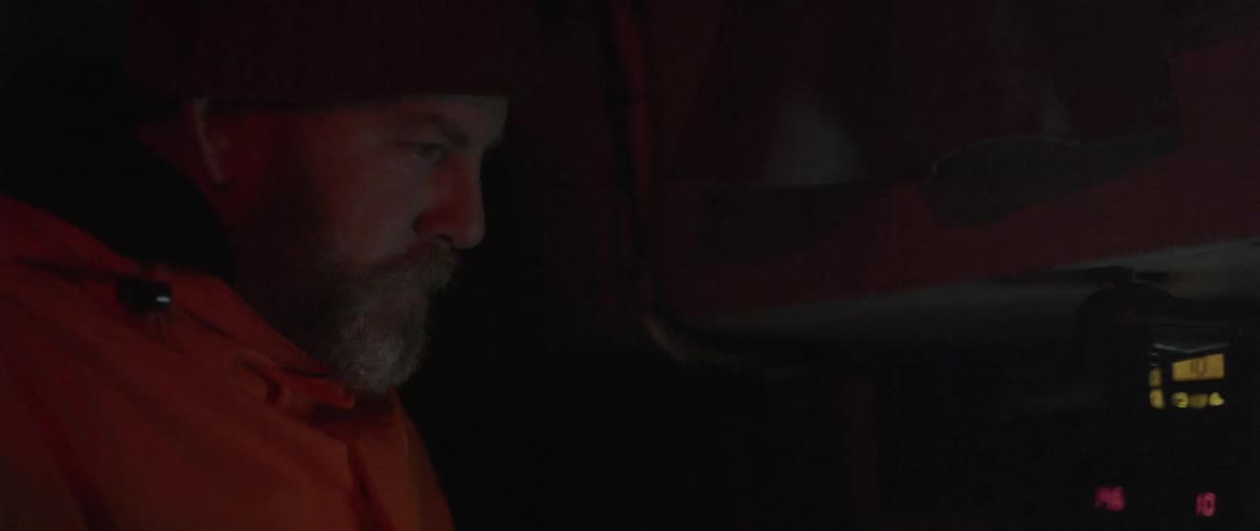 A man is looking ahead in a dark room