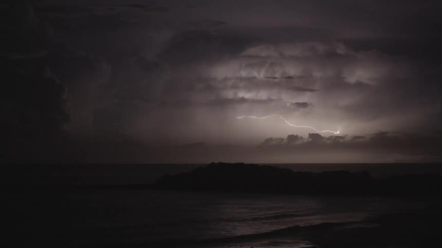 Dark storm clouds are illuminated by numerous bolts of lightnight at night