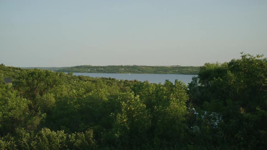 Forest on both sides of the water surrounds scattered buildings