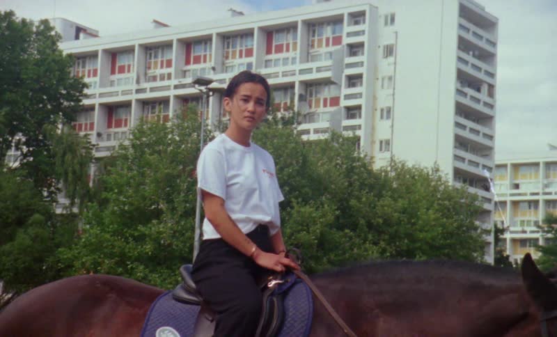 A lady sitting on a saddled horse during the day