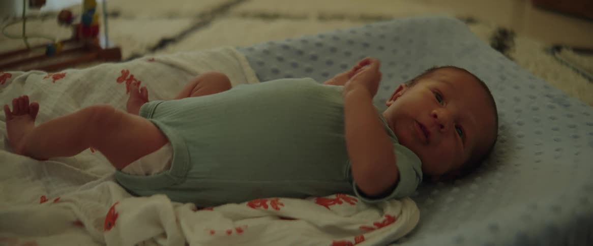 An infant is lying on a cot and moving its head arms and legs
