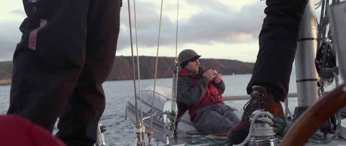 A man is taking photographs leaning on the back of a ship