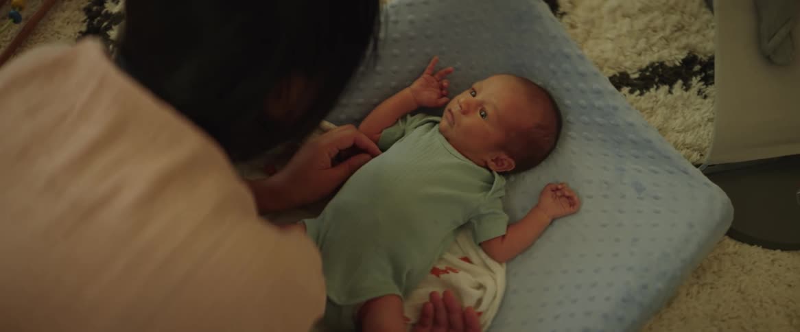 A mother caring his newvborn baby while he is lying down
