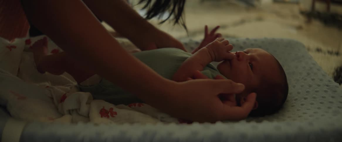 A woman picks up a baby from the cradle on her lap